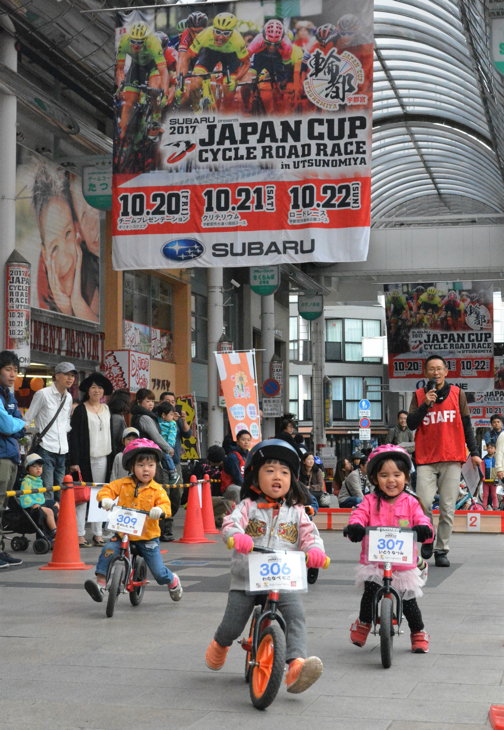 ジャパンカップのビッグフラッグがたなびくオリオン通りを走る子どもたち